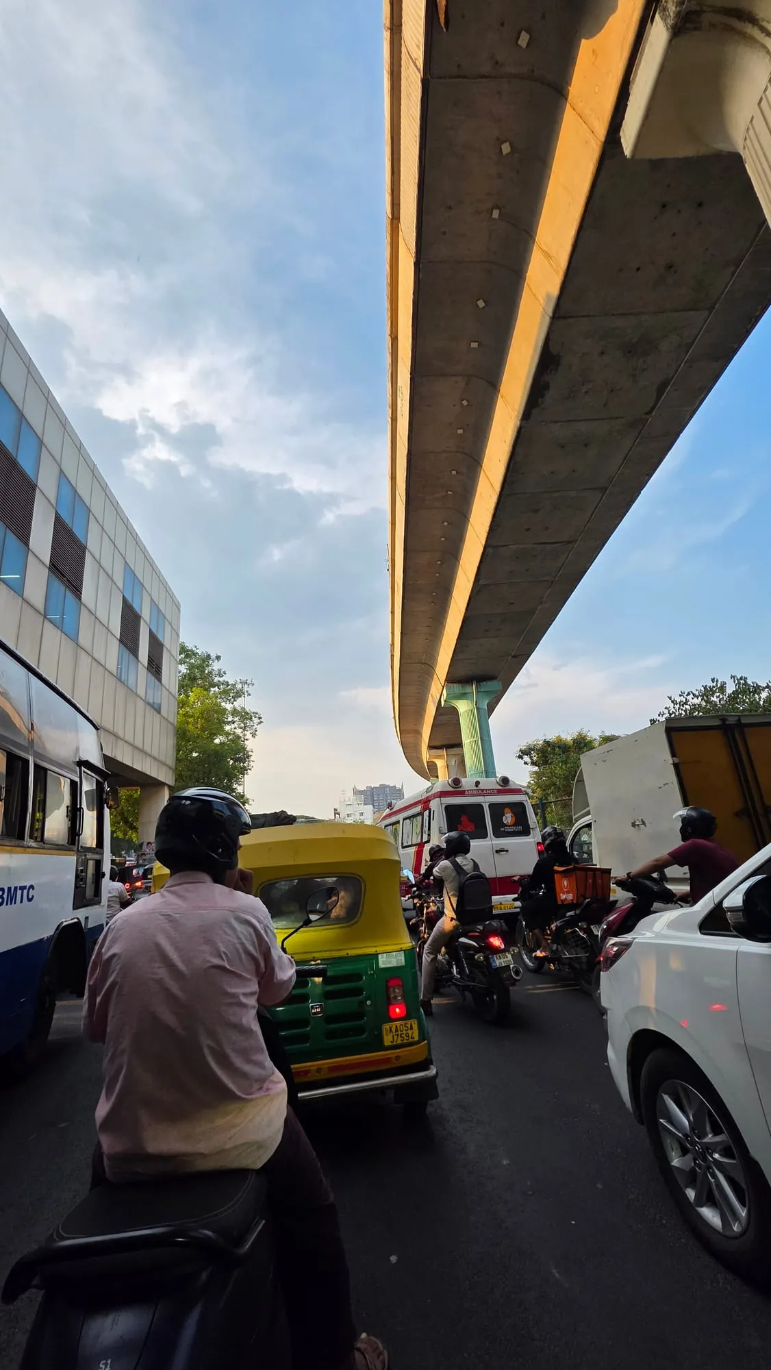 Traffic under a flyover in Bengaluru, with a bus and an auto-rickshaw