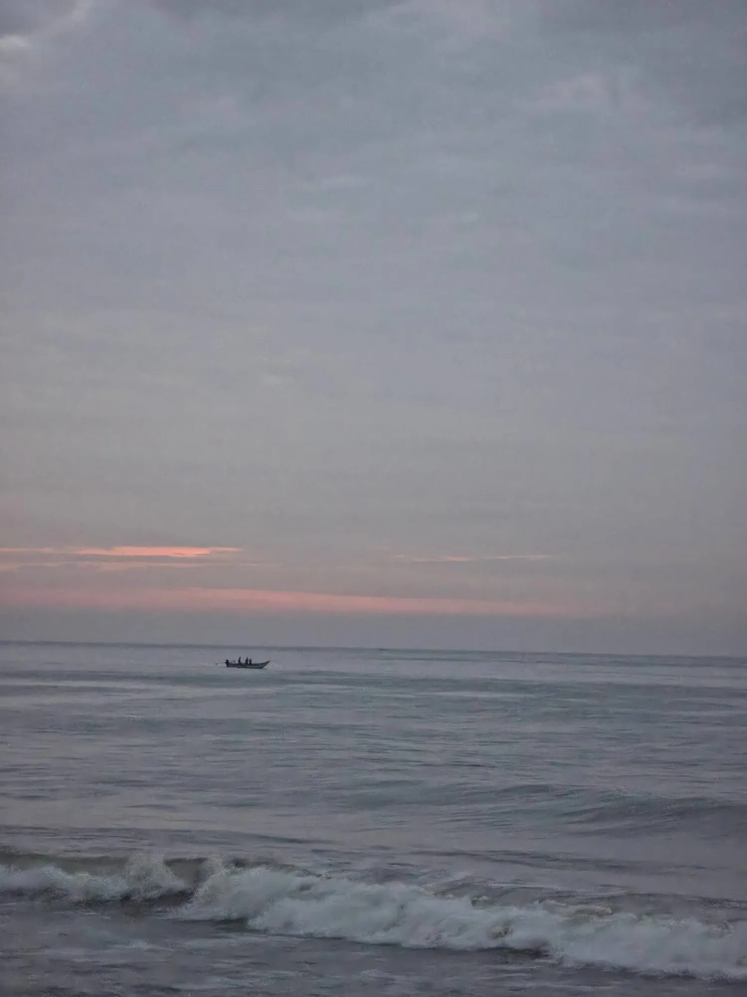 The sea at dawn with a small boat on the horizon